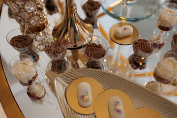 A table with a variety of desserts, including cakes and cookies, arranged in small cups and bowls. The desserts are presented in a way that makes them look like they are on a tray