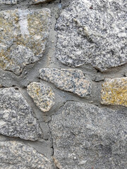 Detail of a textured stone wall constructed with various shapes and colors, showcasing rustic charm