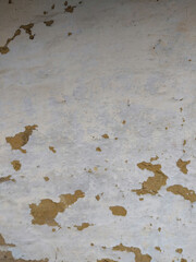 Textured wall with faded paint and patches in a rustic setting during daylight hours