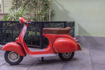 vintage red scooter with brown leather seat in courtyard © Carmen