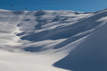 Obraz premium A magical winter landscape near Oeschinensee, Switzerland, with snow-covered peaks towering over the frozen lake. Fir trees dusted in snow line the serene path, creating a peaceful alpine wonderland.