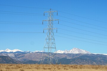 Overhead power lines with blue sky and snowy mountains in the background