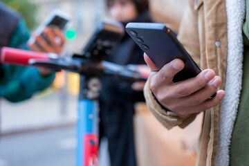 People using smartphones near electric scooters in urban setting