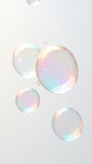 Close-up of colorful, translucent soap bubbles with iridescent reflections floating against a bright white background. Perfect for themes of purity, playfulness, and lightness. Ideal for creative, abs