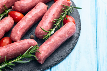 Raw beef sausages with rosemary and tomatoes photography . Top view