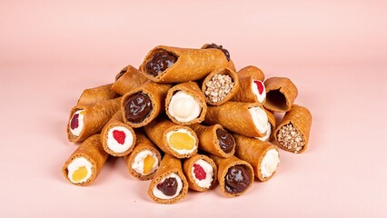 Colorful Cannoli assortment featuring crispy cones filled with delightful cream and fruity surprises against a soft pink backdrop