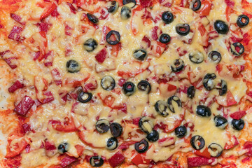 Ready to eat pizza with diced sausage, black olives and tomatoes. Top view and close-up of homemade pizza