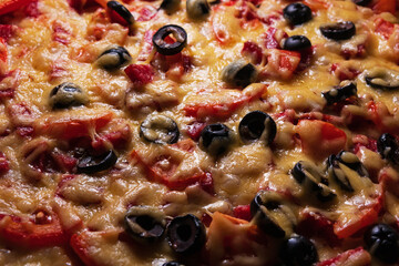 Close-up of homemade pizza with diced sausage, black olives and tomatoes. Ready-to-eat pizza with generous toppings