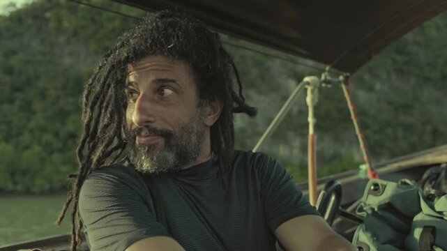 bearded rastaman sitting on a boat sailing dreads locks hair style hippie free