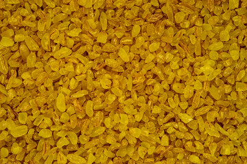 Golden bulgur wheat grains filling the frame: healthy food background