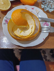 A white plate topped with an orange peel on top of a wooden table