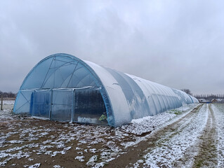A large greenhouse in the middle of a snowy field