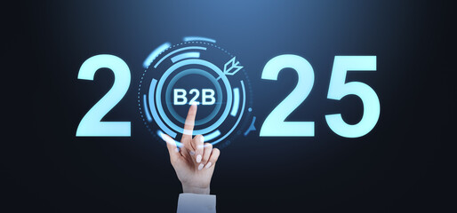 Hand pointing to B2B in a futuristic interface between the numbers 2025 glowing on dark background, representing business strategy and planning.