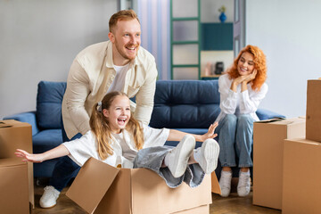 Family and child girl playing and celebrating relocation to own house, having fun while unboxing their stuff