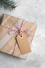 Christmas gift box with craft tag or label, fir tree branch on grey background, top view with copy...