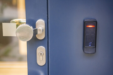 Close up view of door with electric lock with reader of entry system mounted on a house wall