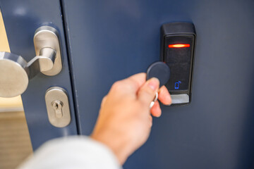Close up view of person using a electric lock key fob to access a building via a reader of entry...