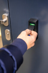 Close up view of person using a electric lock key fob to access a building via a reader of entry...
