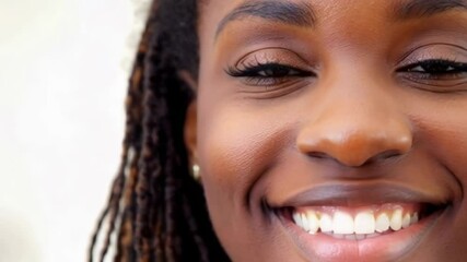 A detailed close-up of a smiling woman with glowing skin and expressive eyes, exuding confidence, joy, and positivity. Vídeo. Horizontal.