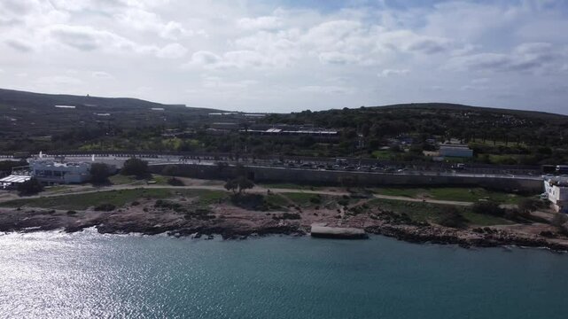 Malta Aerial, white sand beach with umbrelas in November. Approaching roundabout near Ghadira Nature reserve. High quality 4k footage