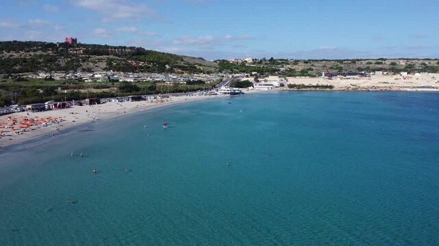 Malta Aerial, white sand beach with umbrelas in November. Approaching roundabout near Ghadira Nature reserve. High quality 4k footage