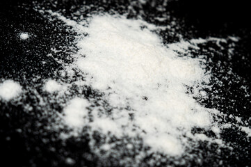 White powder spills onto a dark surface