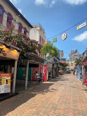 Naklejka premium Charming Pedestrian Street with Shops and Urban Backdrop on a Sunny Day