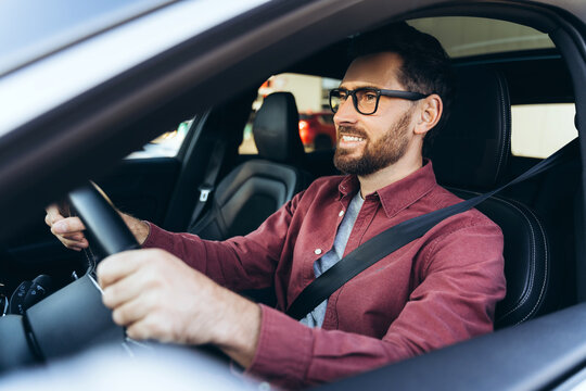 Portrait of smiling, confident bearded man, driver, wearing eyeglasses driving car, looking away