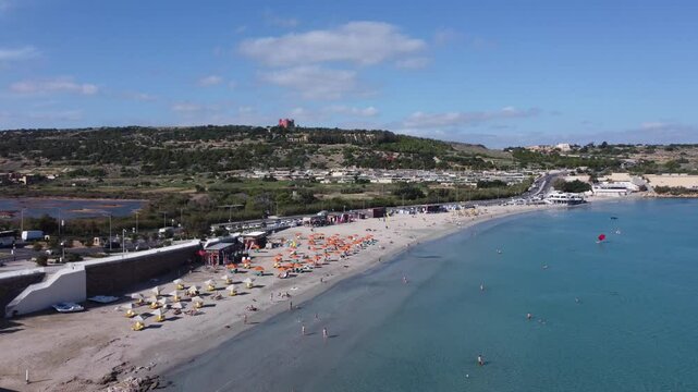 Malta Aerial, white sand beach with umbrelas in November. Approaching roundabout near Ghadira Nature reserve. High quality 4k footage