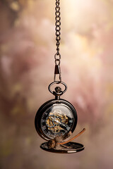 Pocket watch, beautiful pocket watch and a dead rose, hanging by the chain, abstract background, selective focus.