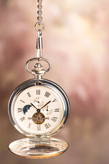Pocket watch, beautiful pocket watch hanging by the chain, abstract background, selective focus.