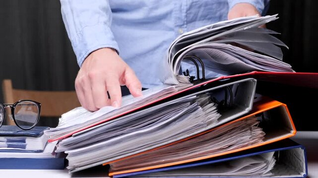 office worker studies a contract, document in the archive, stack of binders