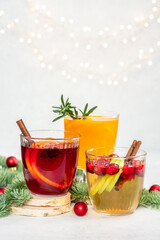 Three glasses of different colored drinks with cinnamon sticks in them