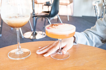 Glass of Cold Orange Mocktail on table,female hand swirling red wine in wine glass,Friends cheering with wineglasses.