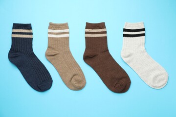 Different comfortable socks on light blue background, flat lay