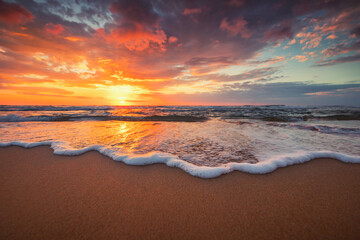 Close up of waves on the beach and a beautiful sunrise over the sea