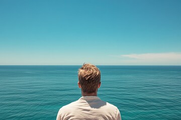 Fototapeta premium A person standing at the edge of the sea, gazing out into the distance