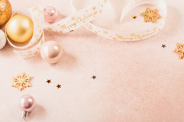 Festive Christmas and New Year background with gold and pink baubles, ribbons and stars. White ribbon with Merry Christmas written. Flat lay, top view with copy space