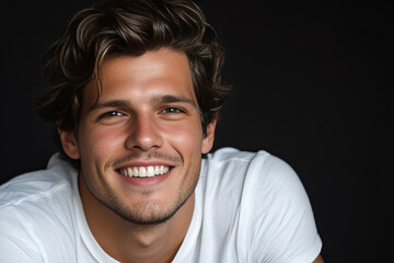 Fototapeta premium Smiling Handsome Man Wearing White T-shirt on a Dark Background, Highlighting Confidence, Positivity, and Modern Casual Style for Personal Branding and Lifestyle Imagery