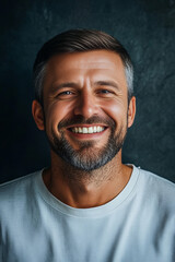 Fototapeta premium Smiling Handsome Man Wearing White T-shirt on a Dark Background, Highlighting Confidence, Positivity, and Modern Casual Style for Personal Branding and Lifestyle Imagery