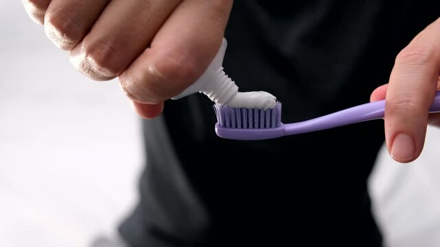 Woman squeezing toothpaste on a toothbrush close up