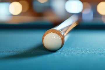 A close-up view of a billiard cue aligned with a white cue ball on a green felt table, capturing precision and readiness in the game.