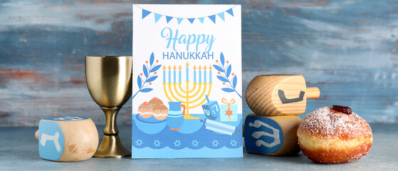 Hanukkah composition with greeting card and traditional decorations on blue wooden background