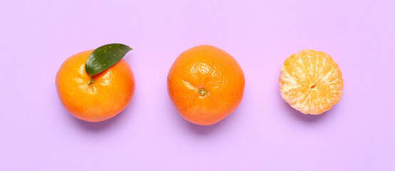 Sweet mandarins with leaf on lilac background