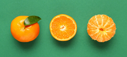 Sweet mandarins with leaf on green background