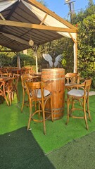 Charming outdoor seating area with wooden chairs and a barrel table. Ideal for creating a relaxed and inviting atmosphere.