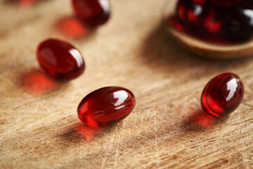 Red krill oil pills or globules on a wooden table
