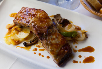 Baked under sauce tasty pork ribs at plate with mushrooms