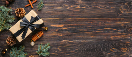 Pine cones with Christmas gift box, fir branches and cinnamon on wooden background