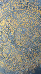 An intricate golden ornamental design embossed on a textured gray surface, featuring floral and geometric patterns. Ideal for luxury design concepts, wallpaper, or decor-related projects.